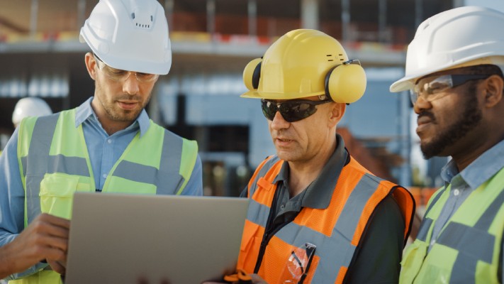 Three Workers Checking Plan on Lap